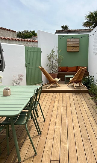 Aménagement terrasse bois avec salon de jardin vert Terrasse bois avec table verte, chaises longues et mur d'accent sauge. Décoration extérieure moderne et cosy.